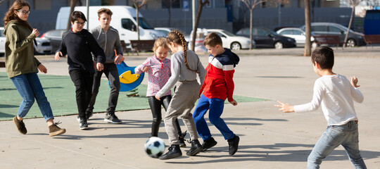 Company of glad children playing football on the street. High quality photo