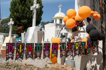 Familiares de difunto celebran el día de los muertos en el cementerio con muchos adornos de fiesta.