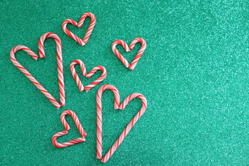 Christmas background. Large and small candy cane hearts on green glitter background.