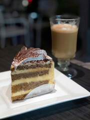 Chocolate cake with cream and cappuccino , blurred restaurant background and copy space
