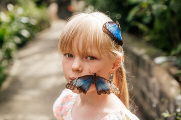 big blue butterfly on the face of a laughing girl, happy childhood.
