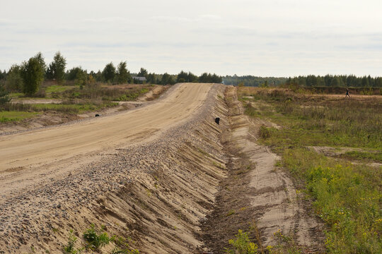 Compacted soil in the embankment during road construction. A mountain of sand. Embankment for the construction of the highway. Sand on the road. Long new sandy dirt road in the countryside