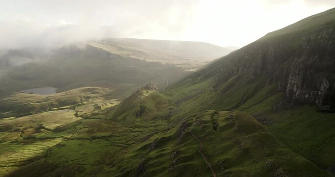 A beautiful sunset illuminates the mountains of the Quairing lost in clouds and fog in the Isle of Skye of Scotland