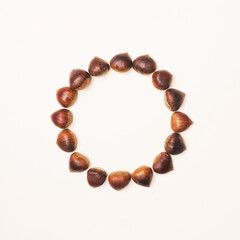 Beautiful brown chestnuts with central minimal circular creative copy space. Beige background. Minimal arrangemet.