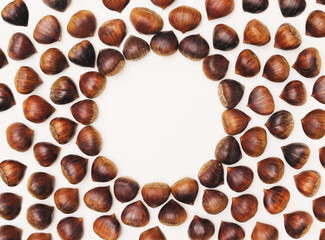 Attractive brown chestnuts arrangement with central minimal circular creative copy space. Beige background.