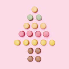 Christmas tree inspired minimal concept. Different colors artisan macarons arrangement. Flat lay with baby pink background.