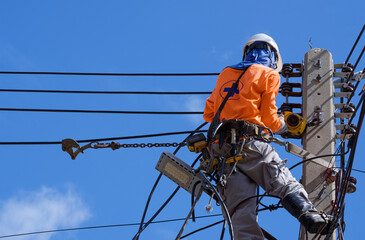 Low angle view of electrician with safety equipment and various work tools is installing cable...
