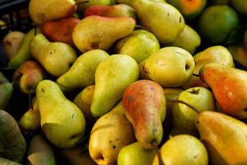 There are many juicy ripe pears on the market counter. Vitamins and health from nature.