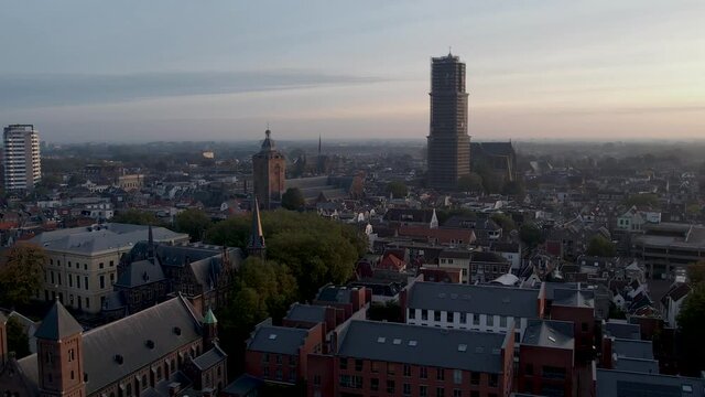 Speelklok museum and De Dom cathedral tower rising up above the rooftops of medieval historic city center of Utrecht in The Netherlands at sunrise. Aerial urban picturesque 60fps at normal speed.
