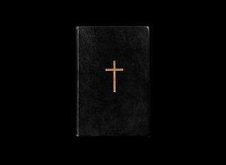 Close old vintage black Holy bible with golden cross on cover isolated on black background. Black book