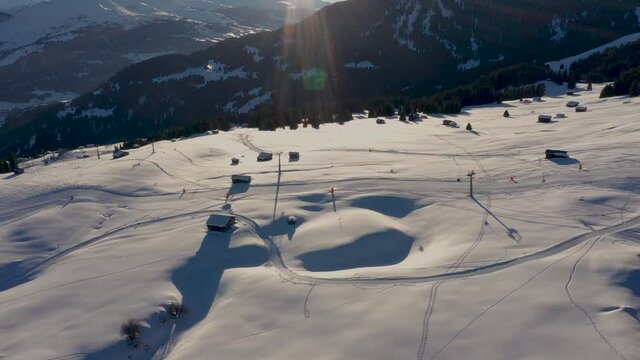 Aerial view of skiers on ski slopes. Golden Sun Light at Sunset in Mountains. Beautiful Sunny evening.