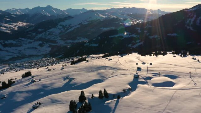 Aerial view of skiers on ski slopes. Golden Sun Light at Sunset in Mountains. Beautiful Sunny evening.