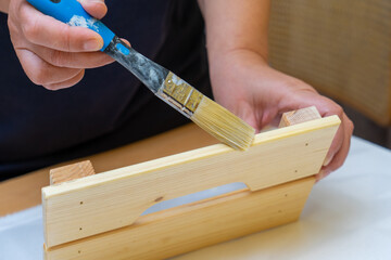 Girl varnishes a wooden detail.