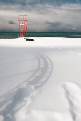 Red lifeguard tower construction on the beach covered with snow