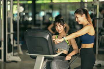 Fototapeta premium Two beautiful fitness woman working out in gym together.