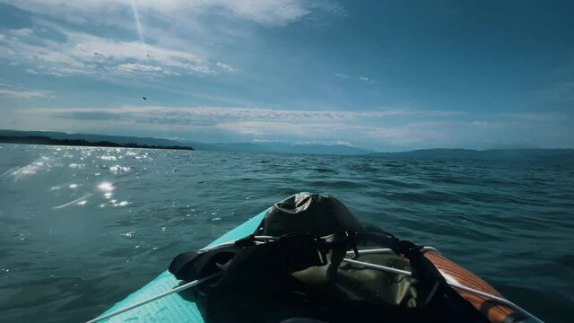 Paddel on SUP on big lake in Germany. Touristic Watersport Adventure Stand up paddle on Bodensee with view on Swiss Mountain. Wet bag, and swim vest. POV.
