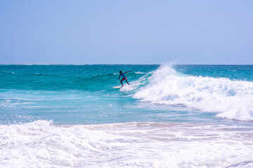 Young man seen riding wave with his surfboard