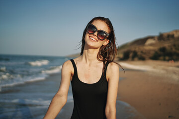 cheerful woman in a black swimsuit walking along the beach tropics summer