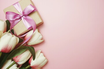 Gift boxes with pink ribbon and tulip flower bouquet on pink background