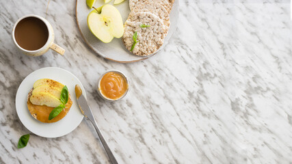 Crounchy buckwheat and rice snack with almond butter and apple decorated with cinnamon and basil on table.Large image with copy space