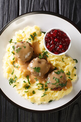 Lihapullat Traditional Finnish Meatballs with mashed potatoes and lingonberry jam close-up in a plate on the table. Vertical top view above