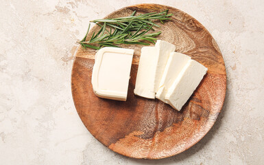 Plate with cut feta cheese and rosemary on light background