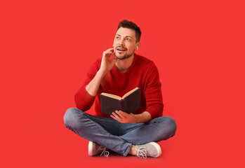 Man with earphones and book on color background