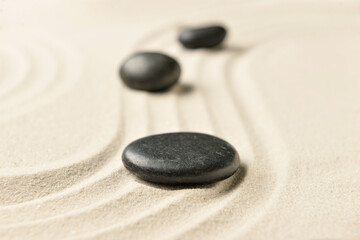 Fototapeta na wymiar Black spa stones on light sand