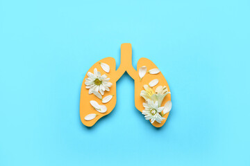 Paper lungs with fresh flowers on blue background