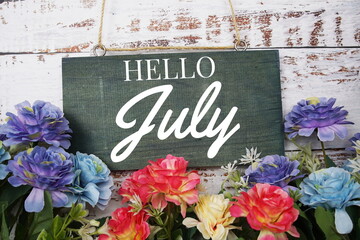 Hello July typography text decorate with flower on wooden background