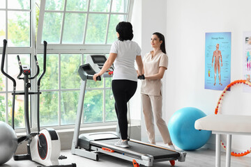 Fototapeta premium Mature woman training on treadmill in rehabilitation center