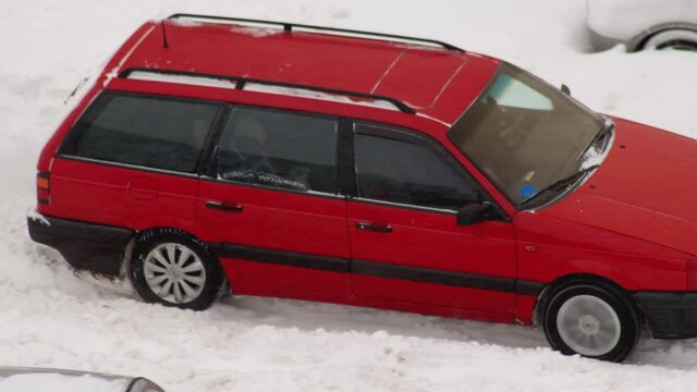 A passenger car slips in the snow in winter and tries to leave. Wheel slip on ice on winter tires. Blizzard, close-up
