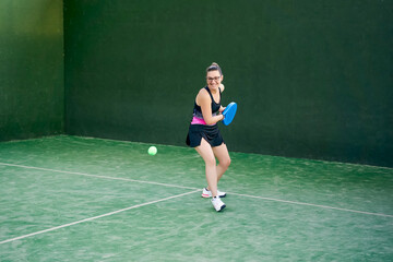 Sportswoman hitting padel ball with racket