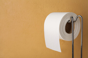 Holder with soft toilet paper roll on color background, closeup