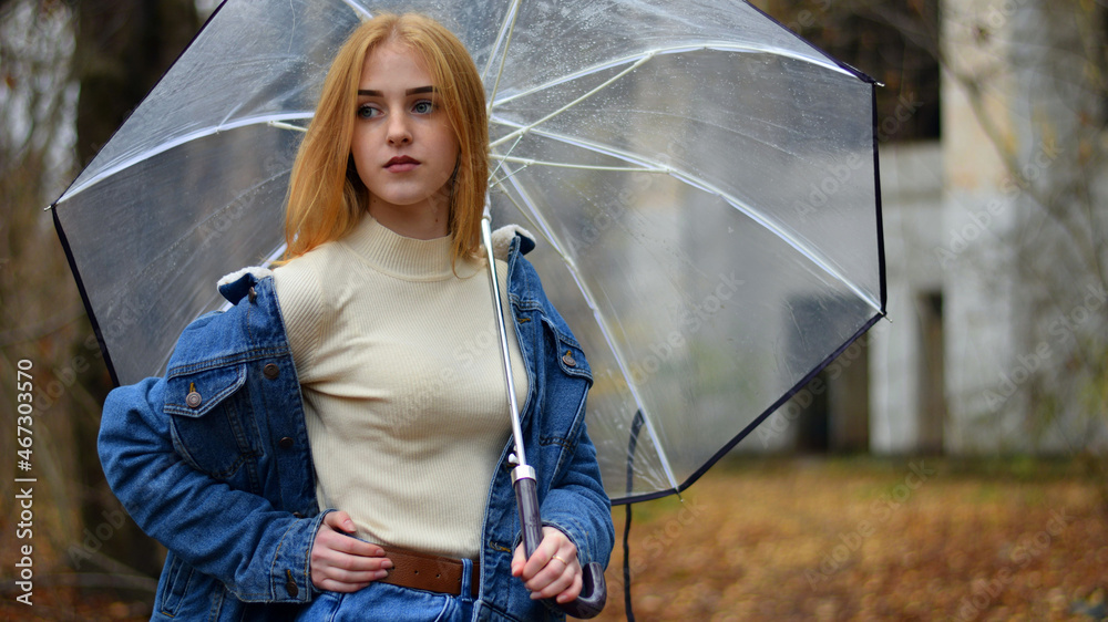 Wall mural young girl with umbrella walking in at beautifu autumn park. modern girl in casual clothes walks thr