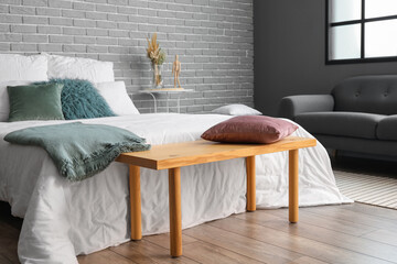 Wooden bench with pillow in interior of modern bedroom