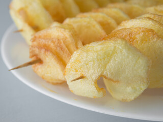 Fried sliced twist potatoes on the wooden sticks. 