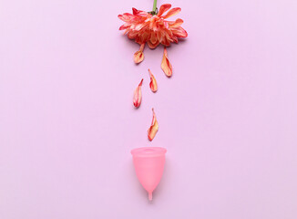 Menstrual cup and flower on color background