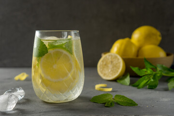 Fresh homemade lemonade on dark gray background. Slices of lemon and mint in glass of ice.
