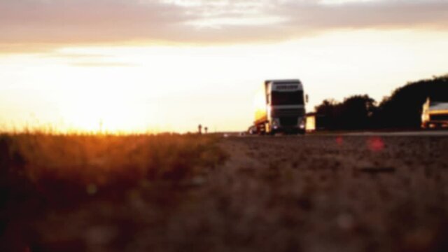 A truck with a trailer carries a groupage cargo on the highway against the backdrop of sunset. Concept of classification of transported goods, logistics, cargo handling, autumn, blurry