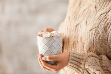 Woman holding cup of delicious cacao on light background, closeup