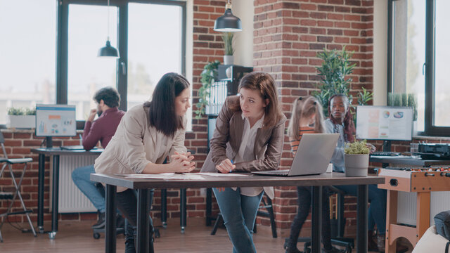 Single mom trying to work with colleague while daughter disturbing work and interrupting discussion. Workmates designing business project and child distracting people at office.