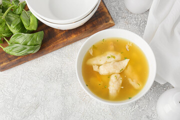 Bowl of delicious dumpling soup on light background