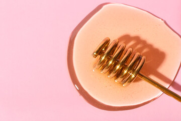 Dipper with sweet honey on pink background, closeup