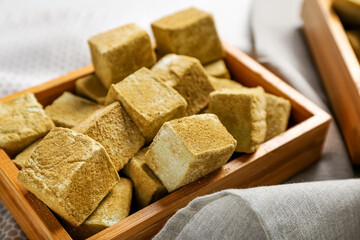 Wooden box with tasty hojicha marshmallows on table, closeup