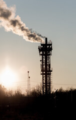 CHP with chimneys, industrial facilities and residential buildings. Environmental pollution. Evening, sunset.