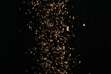 Flying coffee beans isolated on black background. Roasted coffee beans against a flash of light