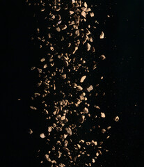 Flying coffee beans isolated on black background. Roasted coffee beans against a flash of light