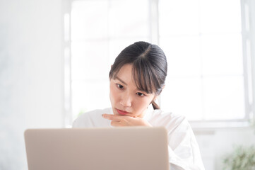 Close-up of an Asian woman distressed while looking at a computer.