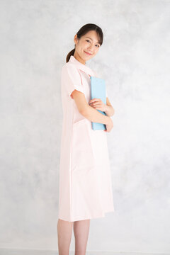 一般看護師や美容系のイメージに使いやすいピンク色のナース服を着た看護師 のポートレート　縦　正面